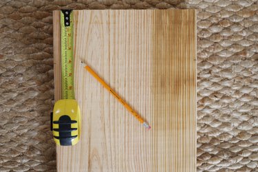 Measuring 4 inches down on each side of wood board and marking it with a pencil