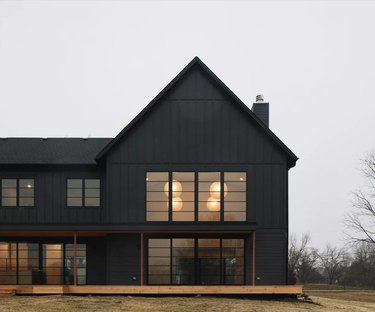 black farmhouse exterior with gray skies