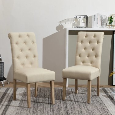 two beige high-back dining chairs with tufted upholstery
