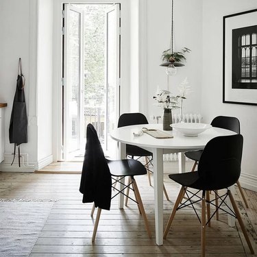 black midcentury-inspired chairs around white round table