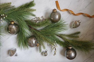 Several DIY mercury glass ornaments with sprig of pine and white berries