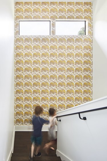 patterned wallpaper in staircase space, with two blurry figures walking past
