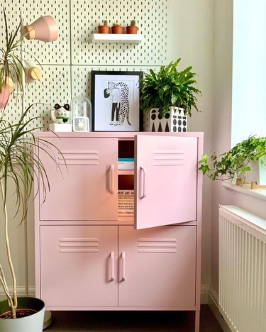 home office with pink storage locker in front of cream pegboards