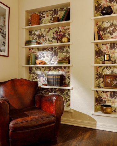 wallpaper with botanical pattern on the back wall of built-in shelving