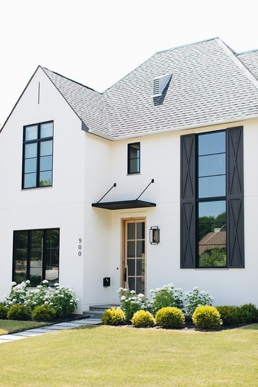 stucco farmhouse exterior with black windows and shutters