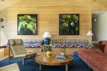 living room with wood paneled walls, sienna sofa and blue rug