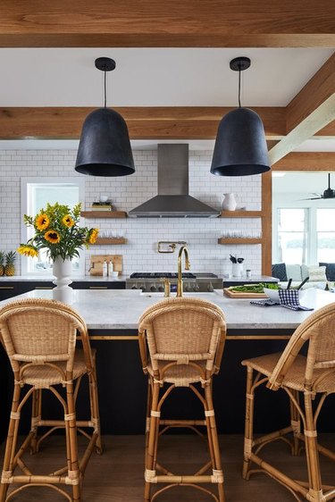 black kitchen island with rattan counter stools