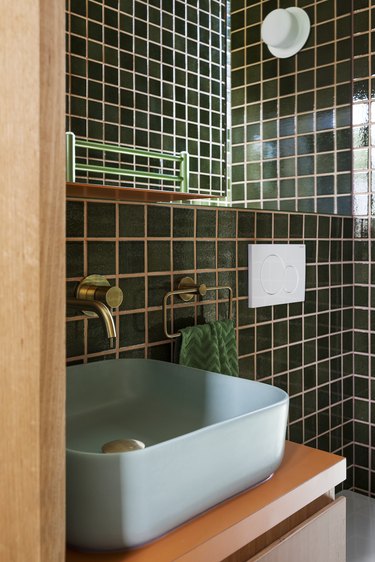 guest bathroom with green wall tile and light green sink
