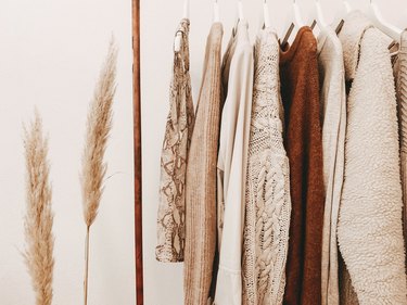 Beige, tan, and orange clothes on a hanging rack