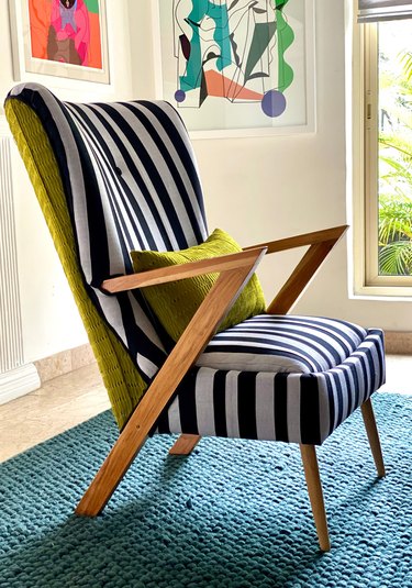 An armchair with a black and white striped fabric on the front and a yellow-green fabric on the back.
