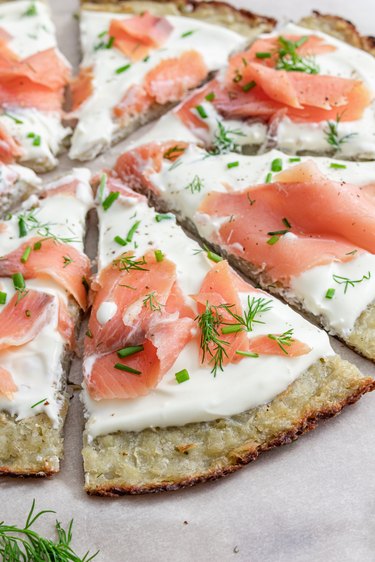 A close-up shot of the Smoked Salmon Latke Pizza on a white marble countertop.