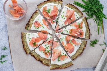 The finished smoked salmon latke pizza on a piece of parchment paper.