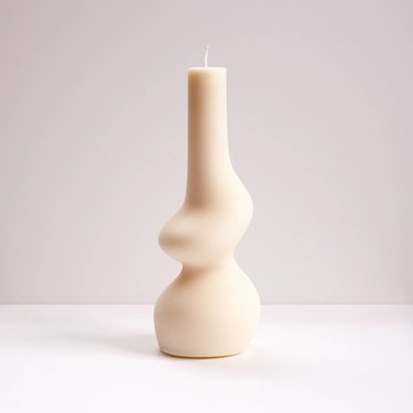 A white candle in a unique organic shape