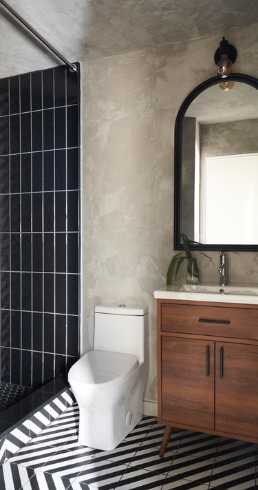 black tiled shower with black and white stripe floor