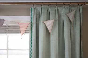 Sage green velvet curtain with green rick rack trim hanging on brass curtain rod with brass curtain rings