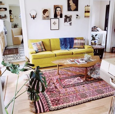 Bright yellow couch and pink rug in living room.