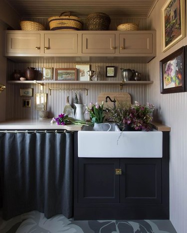 kitchen area with dark lower cabinets and a skirt cabinet, with lighter shelves above