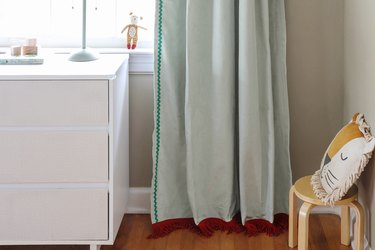 Sage green velvet curtains with brick red fringe trim on the bottom and emerald green rick rack trim on the side