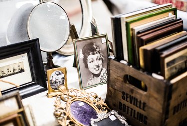 A collection of vintage an antique items, including a table mirror, photo of a woman, and picture frames.