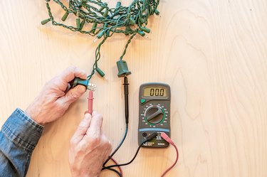 string lights continuity test with with multimeter electrical tester on wood background