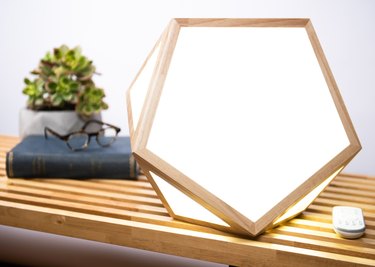 Pentagram shaped light box placed on a bench with plant and book