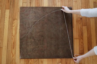 Drawing arc shape on brown fabric with chalk and string