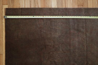 Measuring brown velvet fabric with tape measure