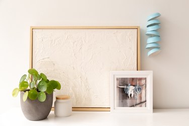 Blue wind chime hanging near artwork and plant