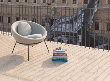 A grey-blue bowl chair outside on a deck with a building behind it