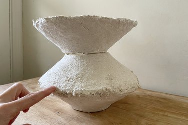 Applying paper mache to smooth the seams of three paper mache bowls glued together