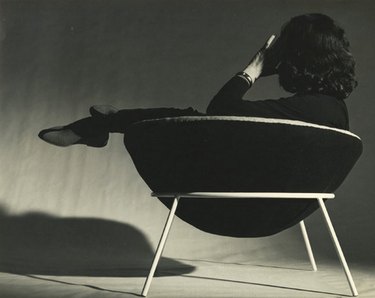 A woman sits in a black bowl chair