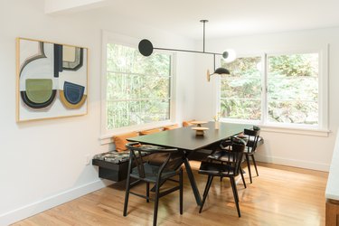 dining area with black chairs and large painting on the wall, near windows
