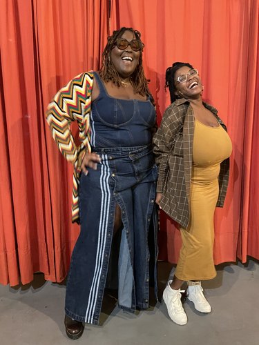 two people in front of a large orange curtain