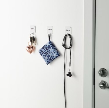 three hooks holding small objects near a door