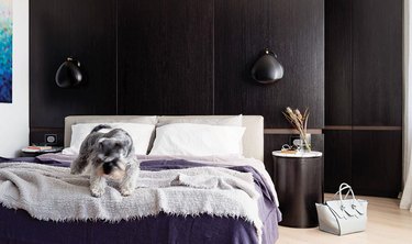 purple bedding in room with dark wood paneling