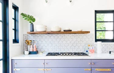Kitchen with white tile backsplash, blue grout, lavender cabinets.