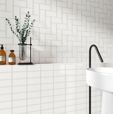 Bathroom with white subway tile, light gray grout, black faucet.
