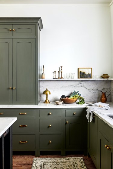 Kitchen with green cabinets and marble counters.