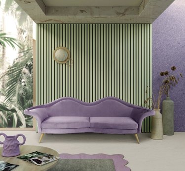 Living room with sage green walls and a purple couch.