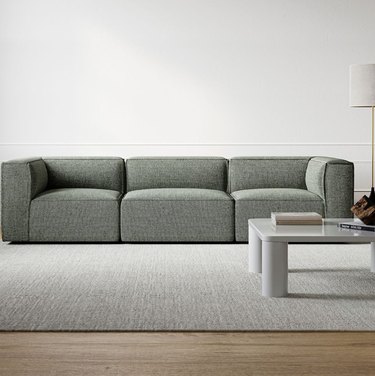 Modern slipcovered sofa, coffee table, rug.