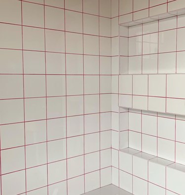 Shower with white square tile, hot pink grout.