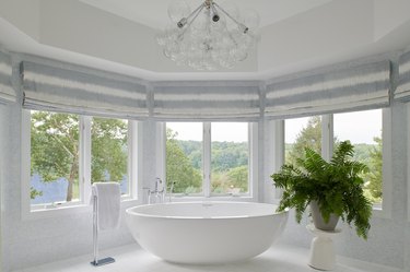 Large and mostly white primary bathroom with contemporary white tub and bubble chandelier