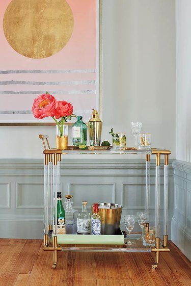 Lucite and brass finish bar cart, bottles, glassware, art, flowers.