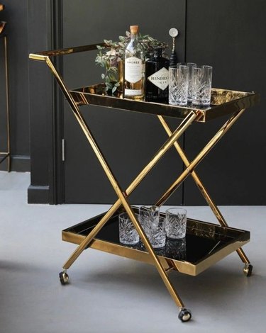 Brass finish bar cart, glassware, bottles.