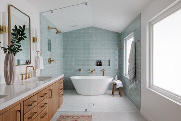 Wet room with light teal tile, golden showerheads, and bathtub