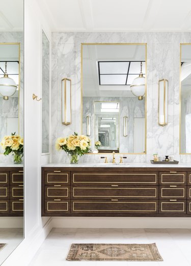 Bathroom by Marie Flanigan Interiors with gold accents and natural wood cabinetry