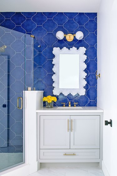 Blue tiled bathroom with gold fixtures and hardware