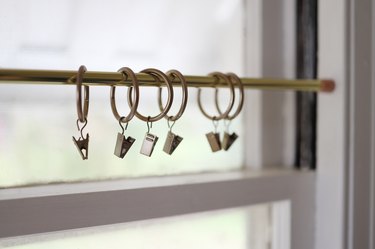 Brass curtain rod in window with brass curtain clips