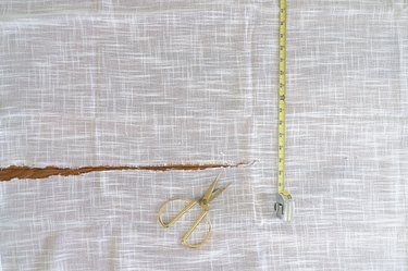 Slit cut in white linen fabric with gold scissors