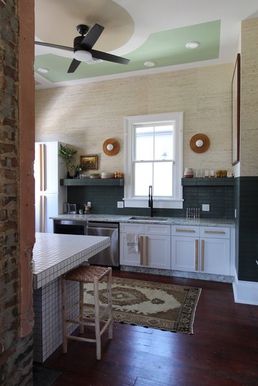 modern kitchen with dark green tile backsplash and cream wallpaper